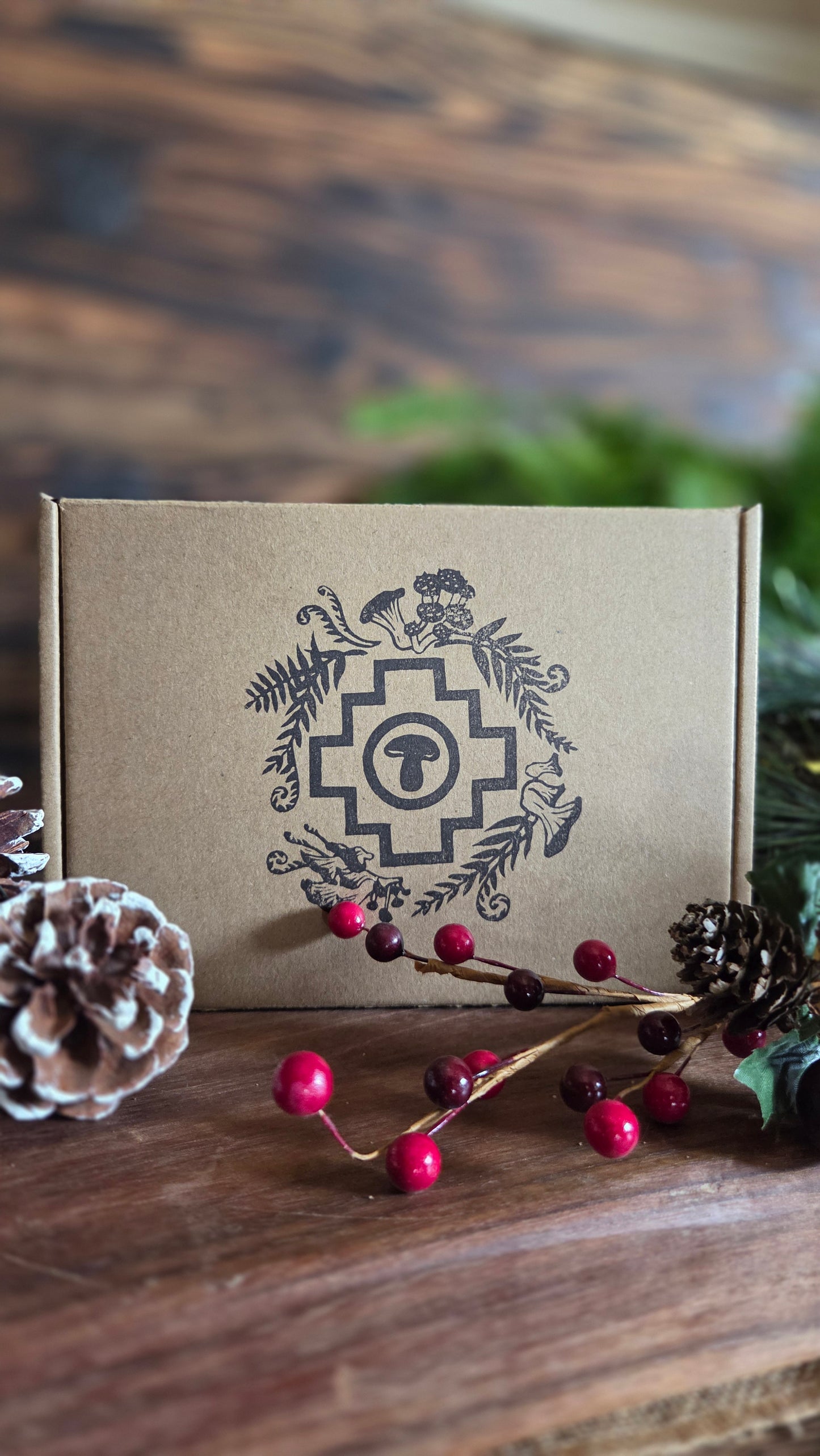 Brown gift box with decorative design on a wooden surface with pine cones and berries.